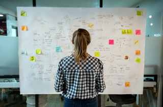 woman in front of large paper filled with notes and post its
